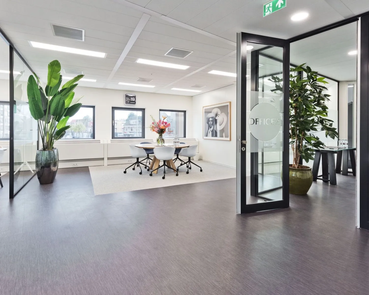 Moderne kantoorruimte te huur in Kennemerhaghe aan de Leidsevaartweg 99 in Heemstede, met glazen wanden, vergadertafel en grote kamerplanten.