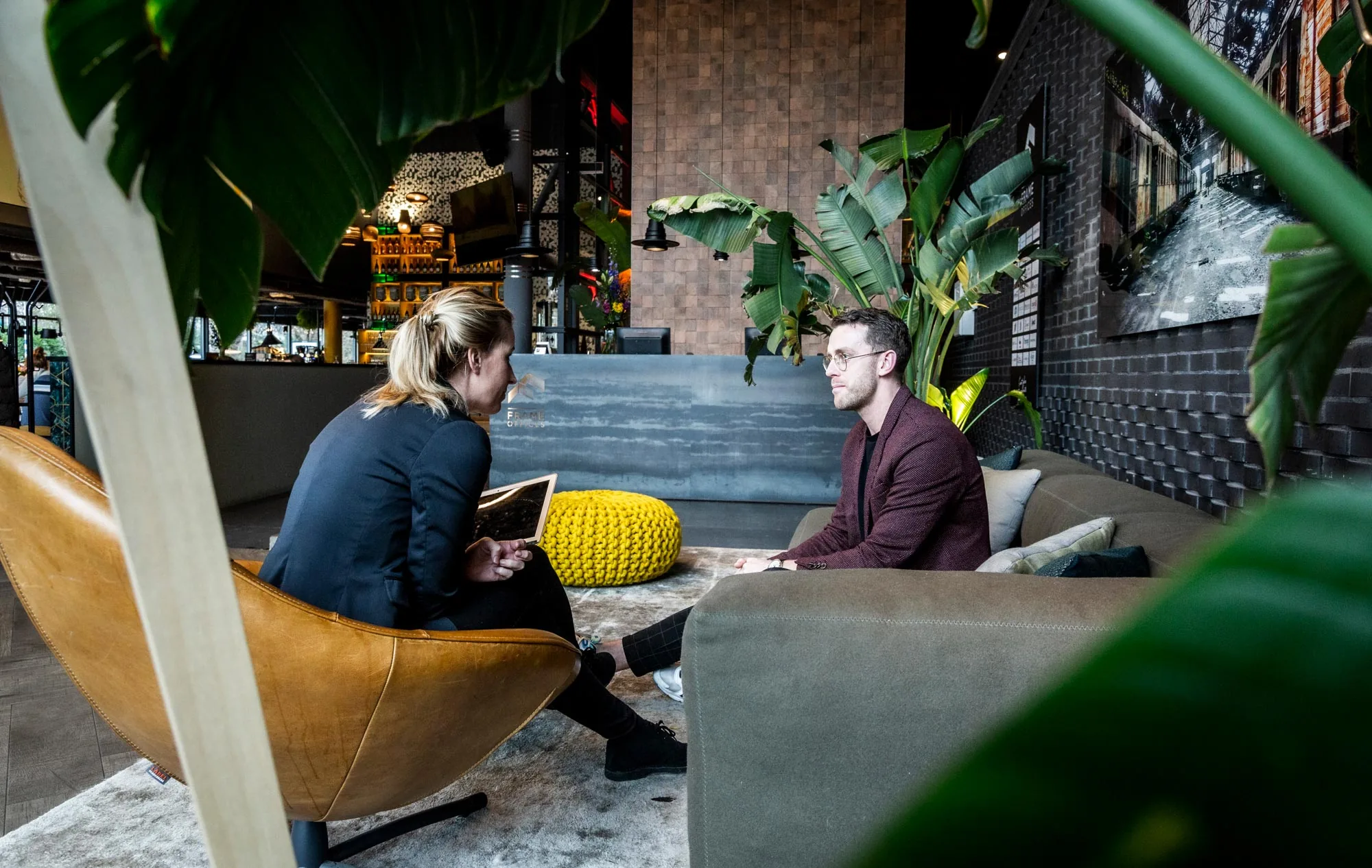 Twee mensen in gesprek in een moderne en sfeervol ingerichte kantoorruimte aan het Kennemerplein in Haarlem.