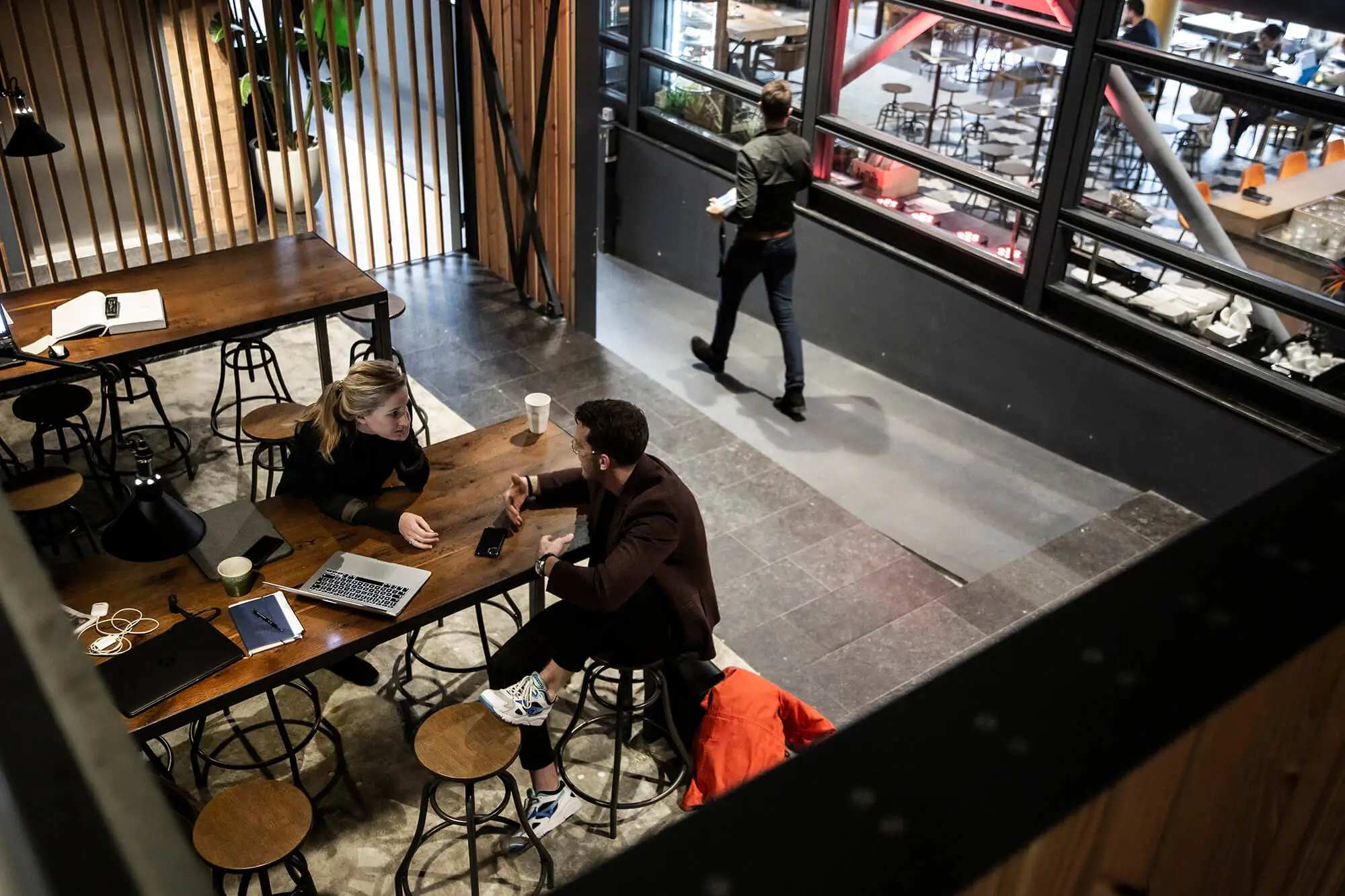 Twee mensen overleggen aan een houten tafel in een moderne kantoorruimte aan het Kennemerplein in Haarlem.