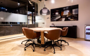Moderne vergaderruimte met ronde houten tafel, leren stoelen en glazen wanden in kantoor aan het Kennemerplein 6-14 in Haarlem.