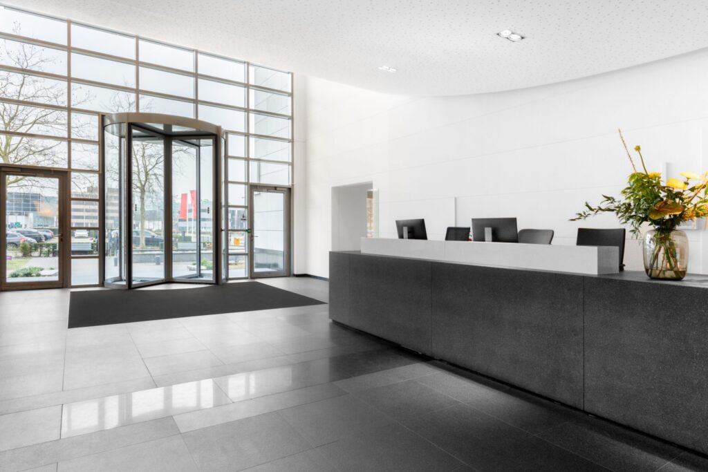 Moderne en lichte entreehal van een kantoorpand aan de Laarderhoogtweg in Amsterdam met receptiebalie en draaideur.