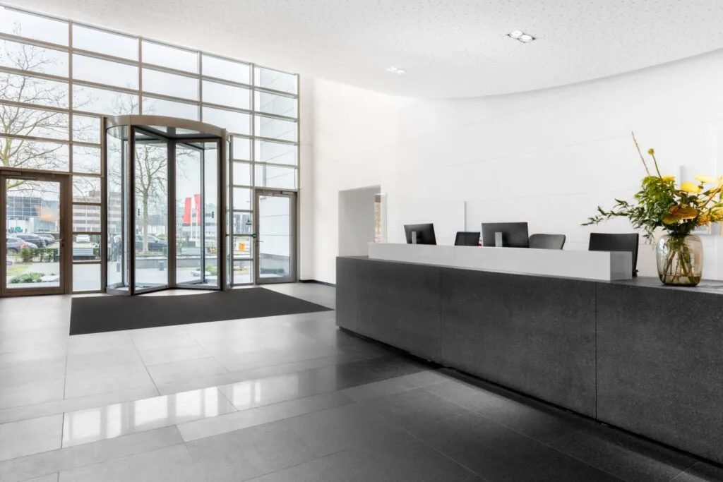 Moderne en lichte entreehal van een kantoorpand aan de Laarderhoogtweg in Amsterdam met receptiebalie en draaideur.
