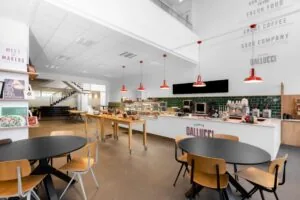 Moderne koffiebar en lunchruimte in een kantoor aan de Laarderhoogtweg in Amsterdam met zitplaatsen en een open balie.