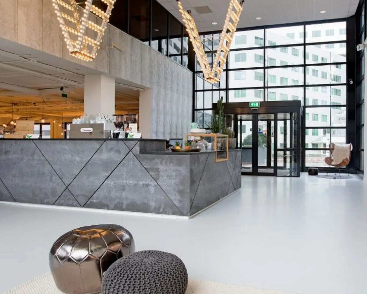 Moderne, lichte ontvangsthal met betonlook balie en zitmeubilair in een kantoorgebouw aan de Marten Meesweg 8-10 in Rotterdam.