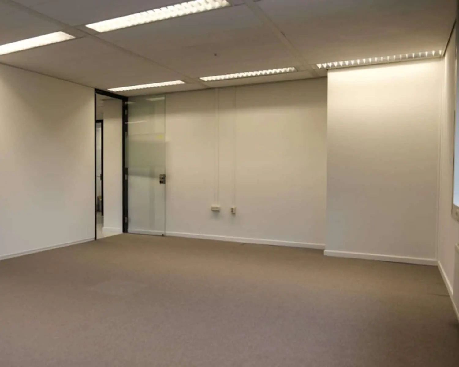 Lege kantoorruimte met tapijtvloer, witte muren en een glazen deur aan de Marten Meesweg 8-10 in Rotterdam.