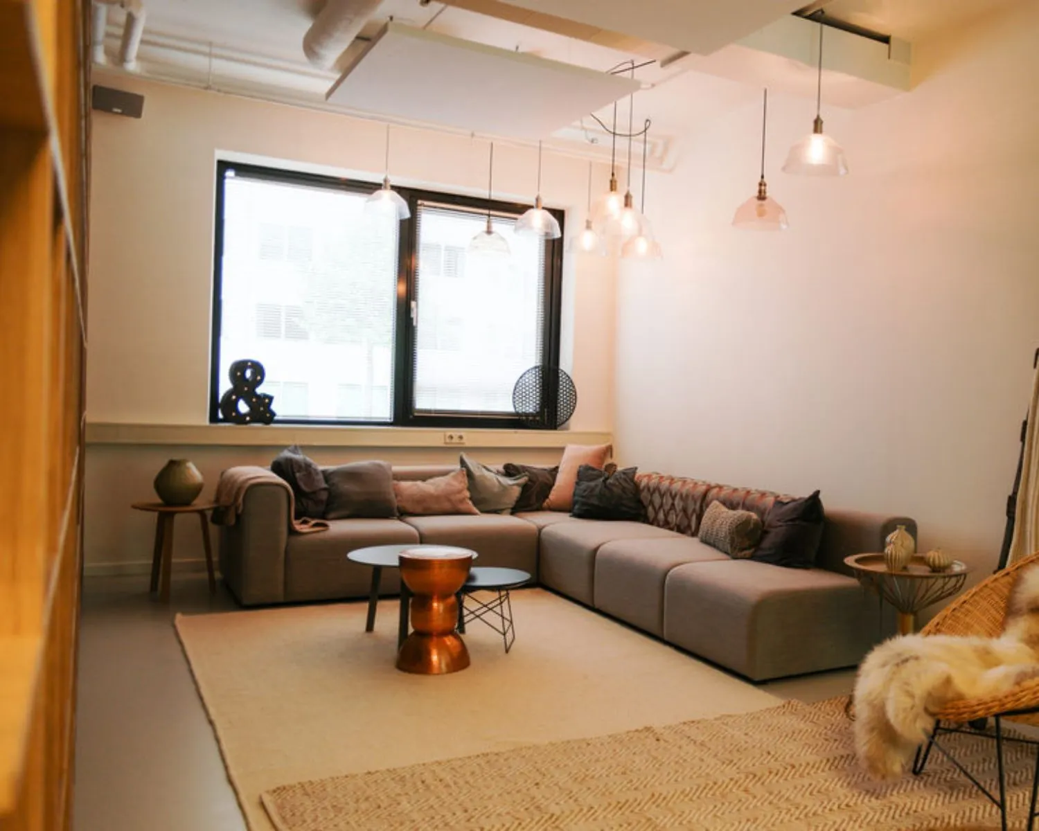 Stijlvol ingerichte loungehoek in een kantoorruimte aan de Marten Meesweg 8-10 in Rotterdam met een grote bank, hanglampen en warme decoratie.