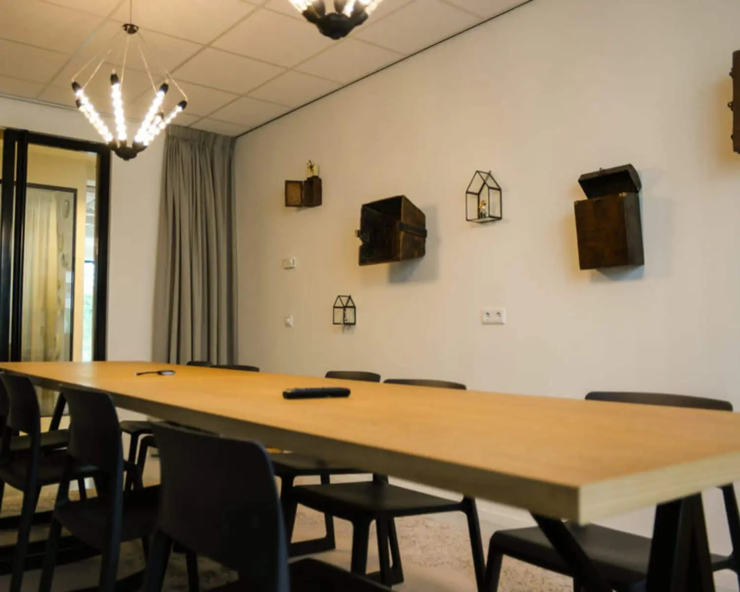 Vergaderruimte in een kantoor aan de Marten Meesweg in Rotterdam met een lange houten tafel, zwarte stoelen en decoratieve wandobjecten.