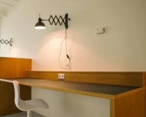 Moderne werkplek met houten bureau, witte stoel en wandlamp in een kantoorruimte aan de Marten Meesweg 8-10 in Rotterdam.