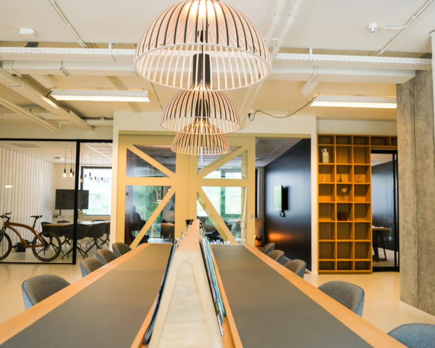 Moderne kantoorruimte aan de Marten Meesweg in Rotterdam met lange vergadertafel, designverlichting en glazen vergaderruimtes.