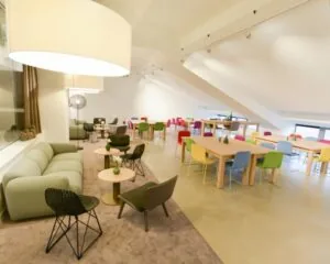 Moderne kantoorruimte in het Olympisch Stadion Amsterdam met kleurrijke stoelen, houten tafels en een loungegedeelte.