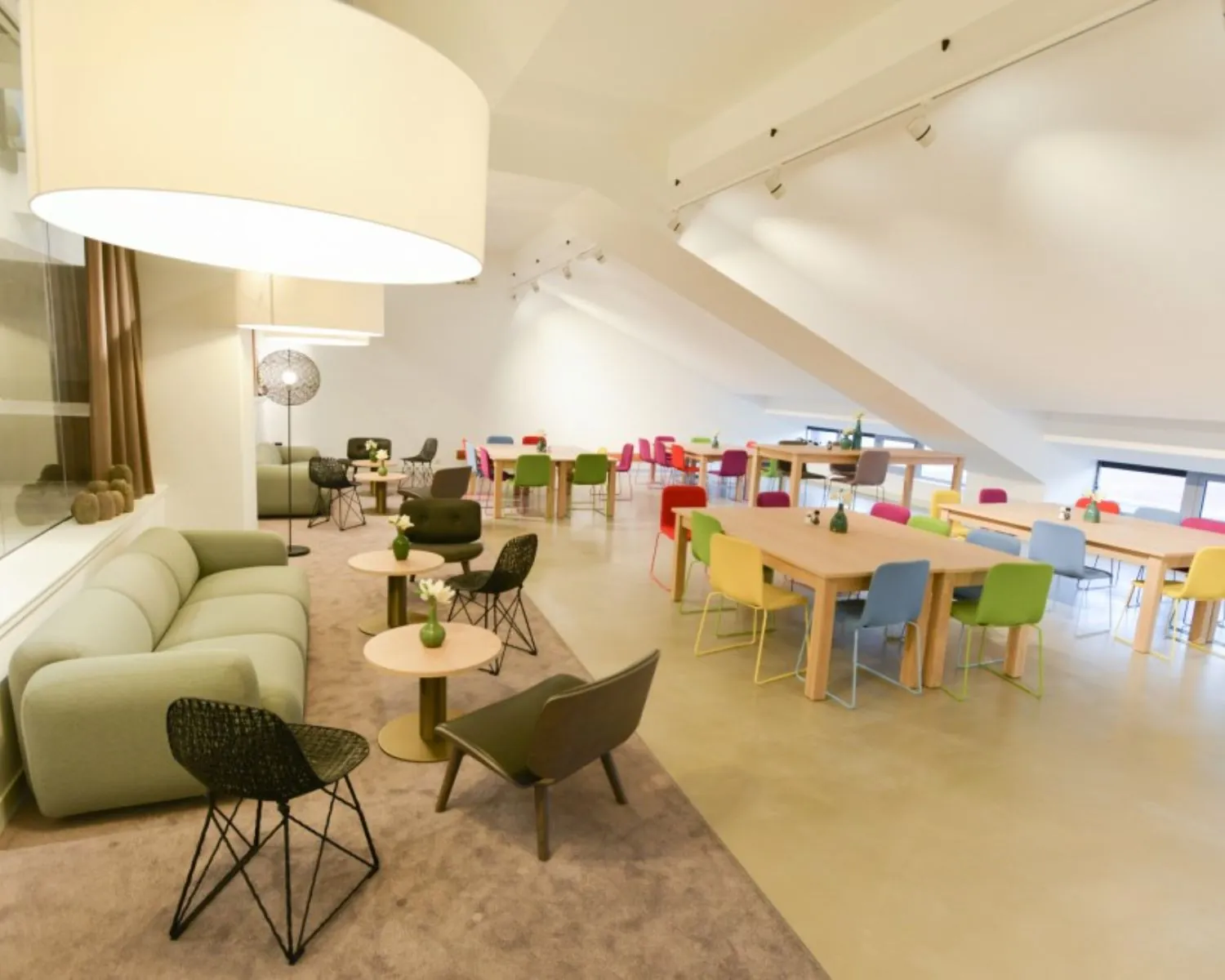 Moderne kantoorruimte in het Olympisch Stadion Amsterdam met kleurrijke stoelen, houten tafels en een loungegedeelte.