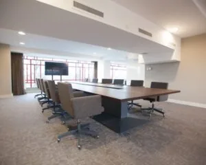 Moderne vergaderruimte met een lange houten tafel, bureaustoelen en een flatscreen, gelegen in het Olympisch Stadion in Amsterdam.