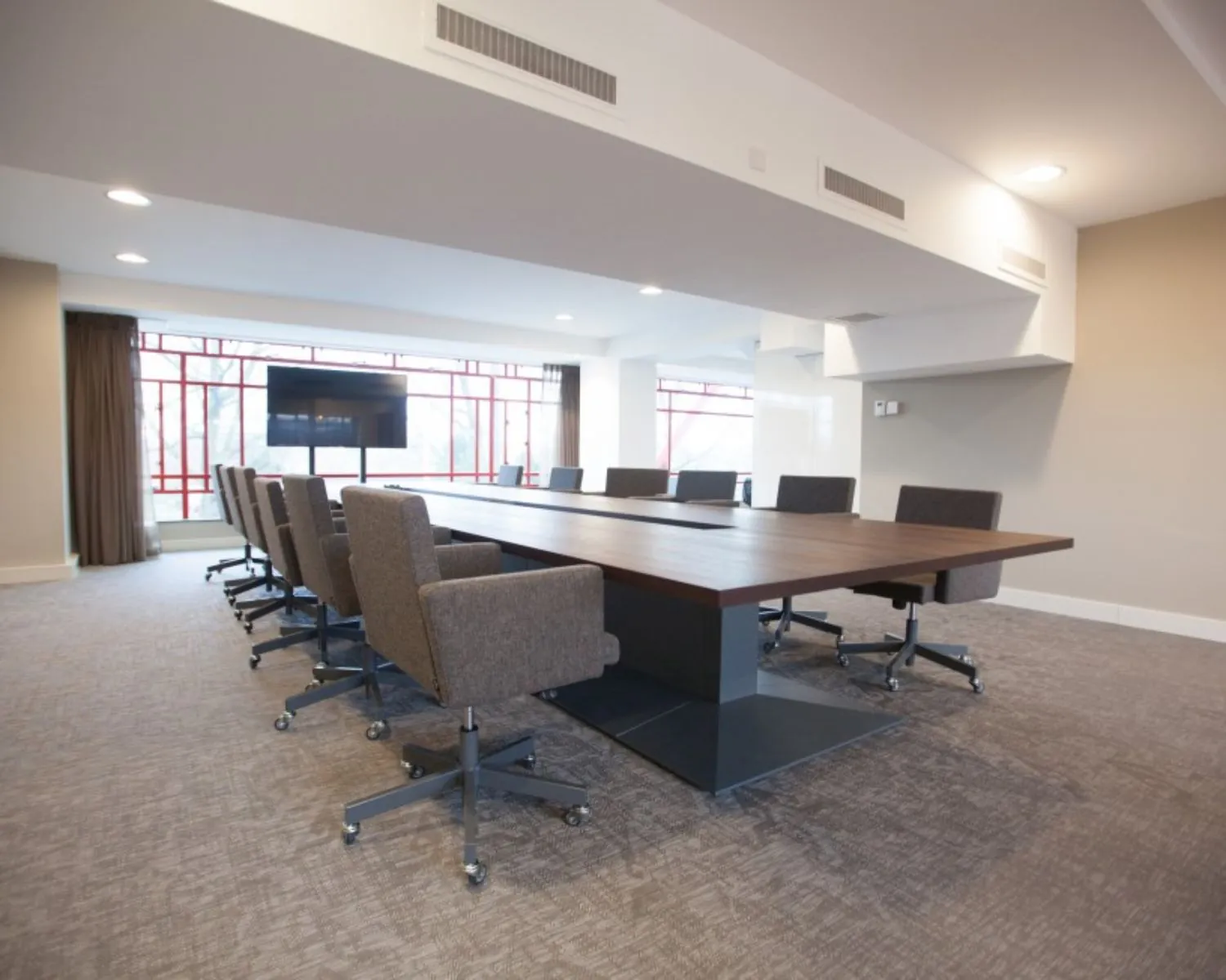 Moderne vergaderruimte met een lange houten tafel, bureaustoelen en een flatscreen, gelegen in het Olympisch Stadion in Amsterdam.