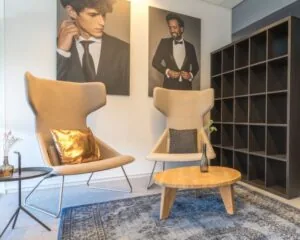 Moderne zithoek in een kantoorruimte aan de Overschiestraat 65 in Amsterdam met designstoelen, een houten salontafel en stijlvolle wandfoto’s.