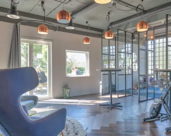 Moderne kantoorruimte aan de Overschiestraat 65 in Amsterdam met grote ramen, glazen scheidingswanden en designmeubilair.