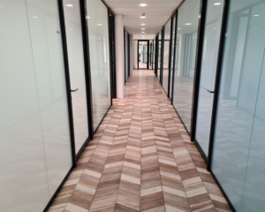 Moderne gang met glazen kantoorwanden en visgraatvloer in een kantoorgebouw aan de Overschiestraat in Amsterdam.
