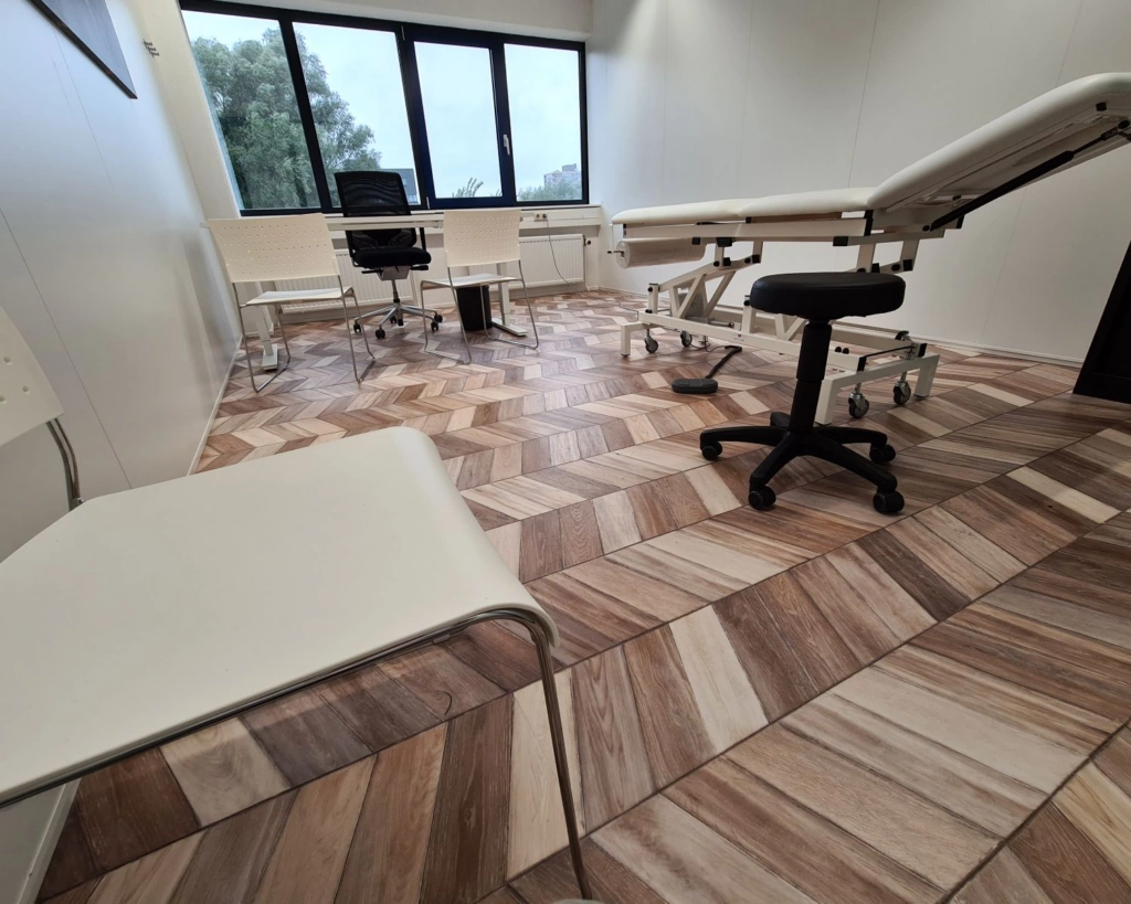 Moderne kantoorruimte te huur aan de Overschiestraat in Amsterdam met bureaus, stoelen, een behandelbank en groot raam.