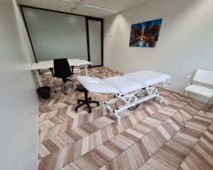 Moderne kantoorruimte te huur aan de Overschiestraat in Amsterdam, ingericht als behandel- of spreekkamer met bureau, behandelbank en stoelen.