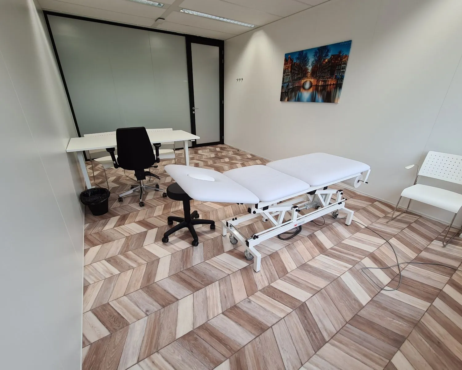 Moderne kantoorruimte te huur aan de Overschiestraat in Amsterdam, ingericht als behandel- of spreekkamer met bureau, behandelbank en stoelen.