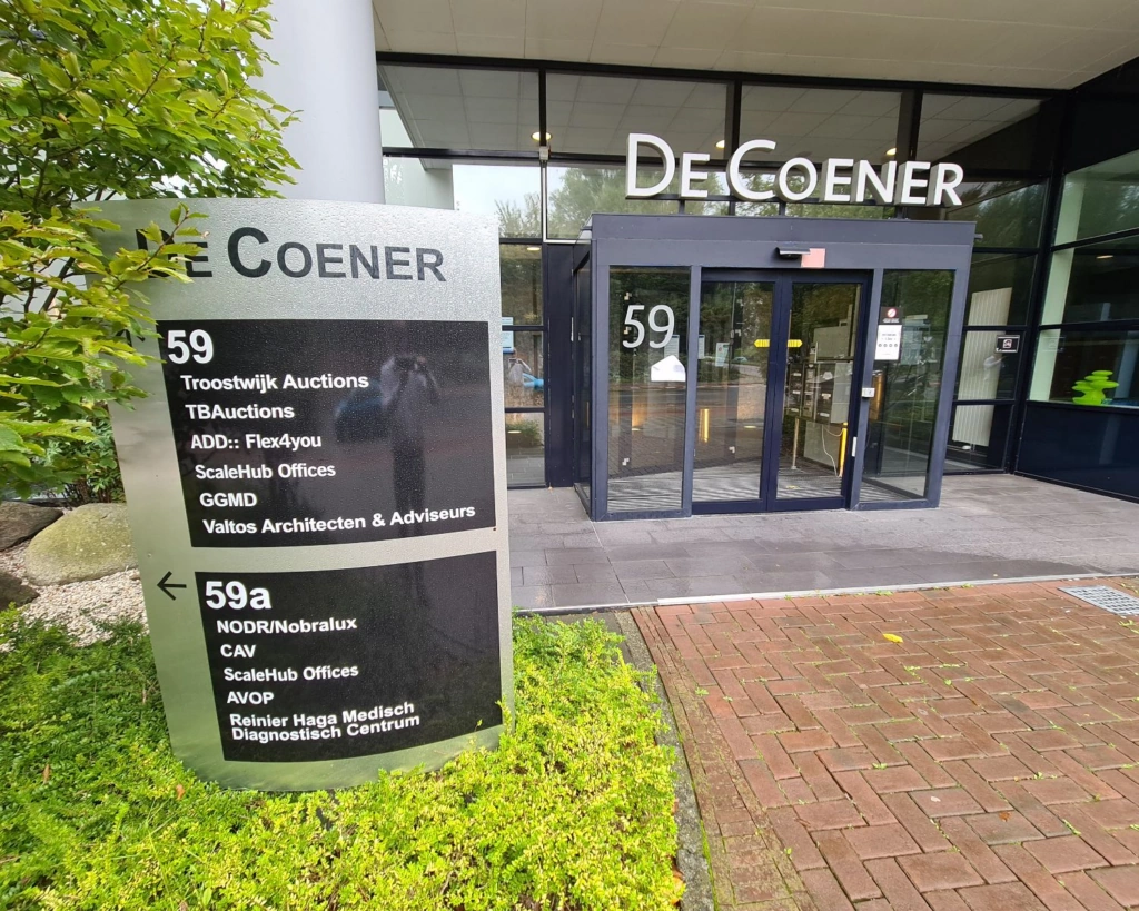 Ingang van kantoorpand De Coener aan de Overschiestraat 59 in Amsterdam met bedrijvenbord bij de entree.