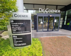 Ingang van kantoorpand De Coener aan de Overschiestraat 59 in Amsterdam met bedrijvenbord bij de entree.