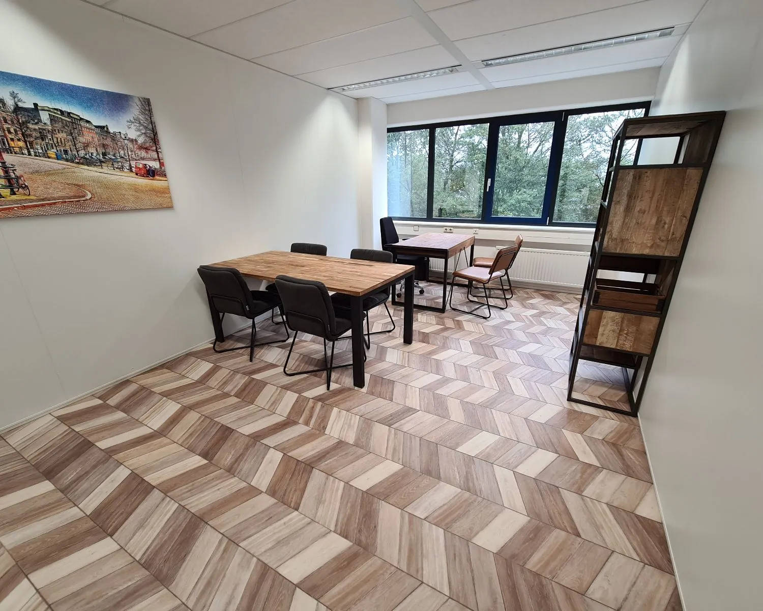 Moderne kantoorruimte met houten tafels, stoelen, een open kast en een groot raam aan de Overschiestraat in Amsterdam.