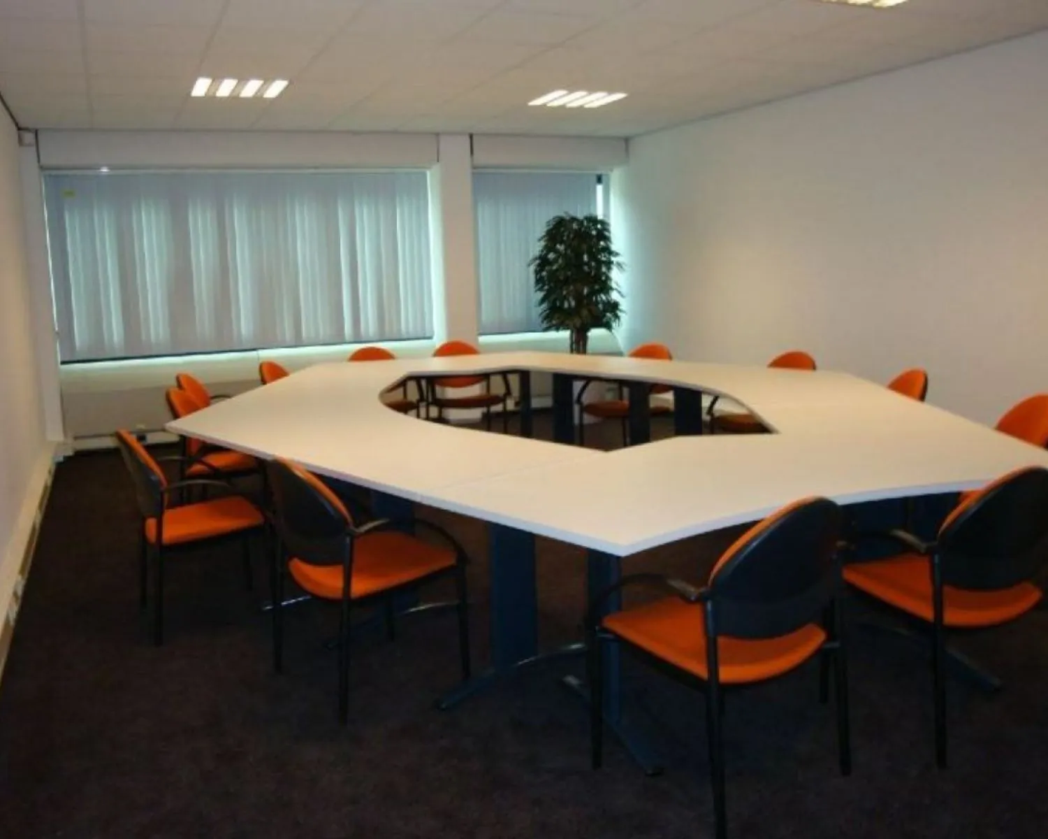 Vergaderruimte met U-vormige tafel en oranje stoelen in een kantoor aan de 's-Gravelandseweg 258.