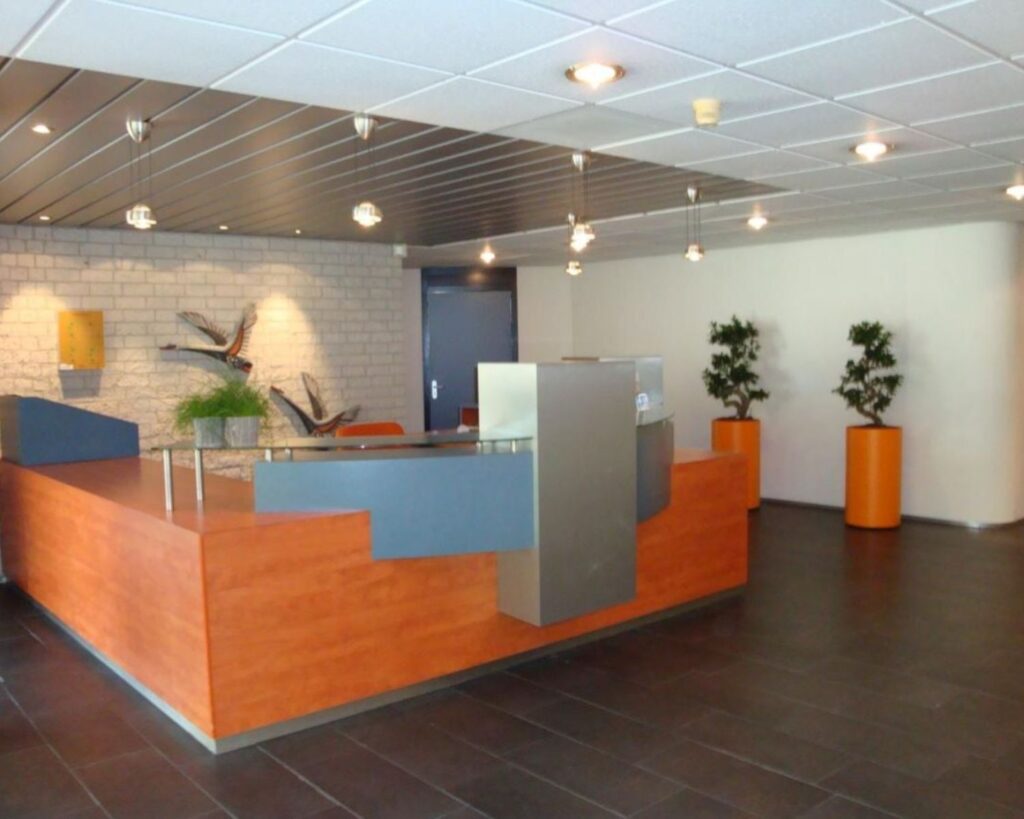 Moderne ontvangstruimte met houten balie, decoratieve planten en wandversiering in een kantoor aan de 's-Gravelandseweg 258.