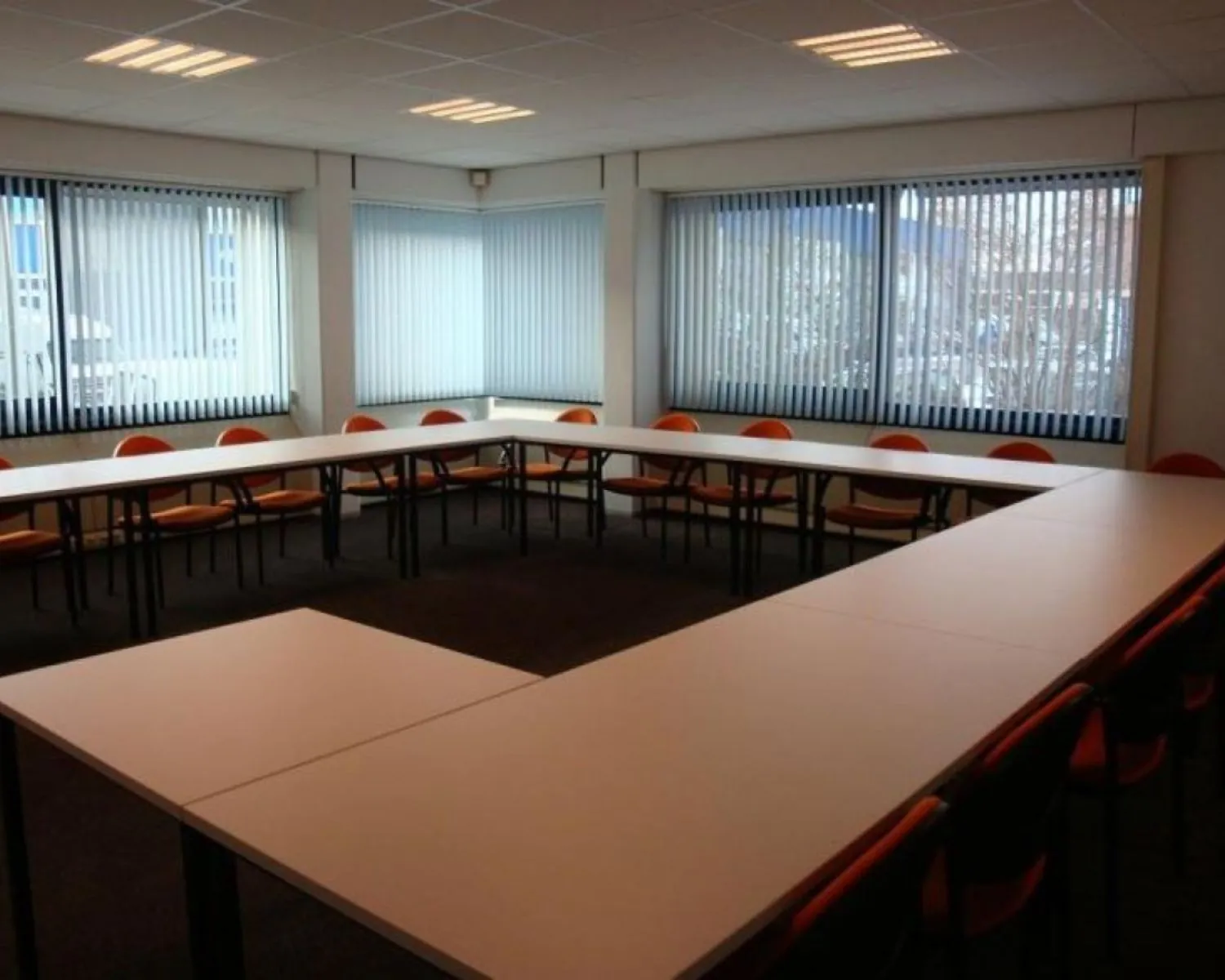 Vergaderruimte met U-vormige opstelling van witte tafels en oranje stoelen aan de 's-Gravelandseweg 258.
