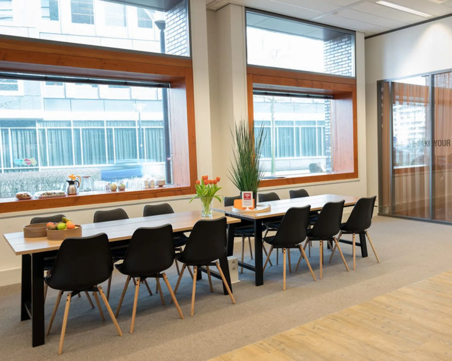 Moderne vergaderruimte met lange tafel, zwarte stoelen en grote ramen in kantoor aan het Smallepad 32 in Amersfoort.