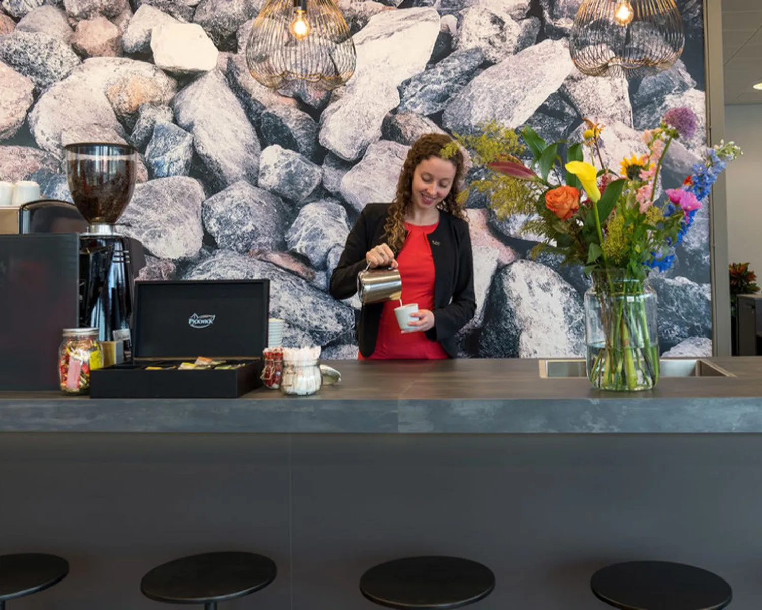 Vrouw schenkt koffie in bij een moderne koffiebar in kantoorruimte aan het Smallepad 32 in Amersfoort.