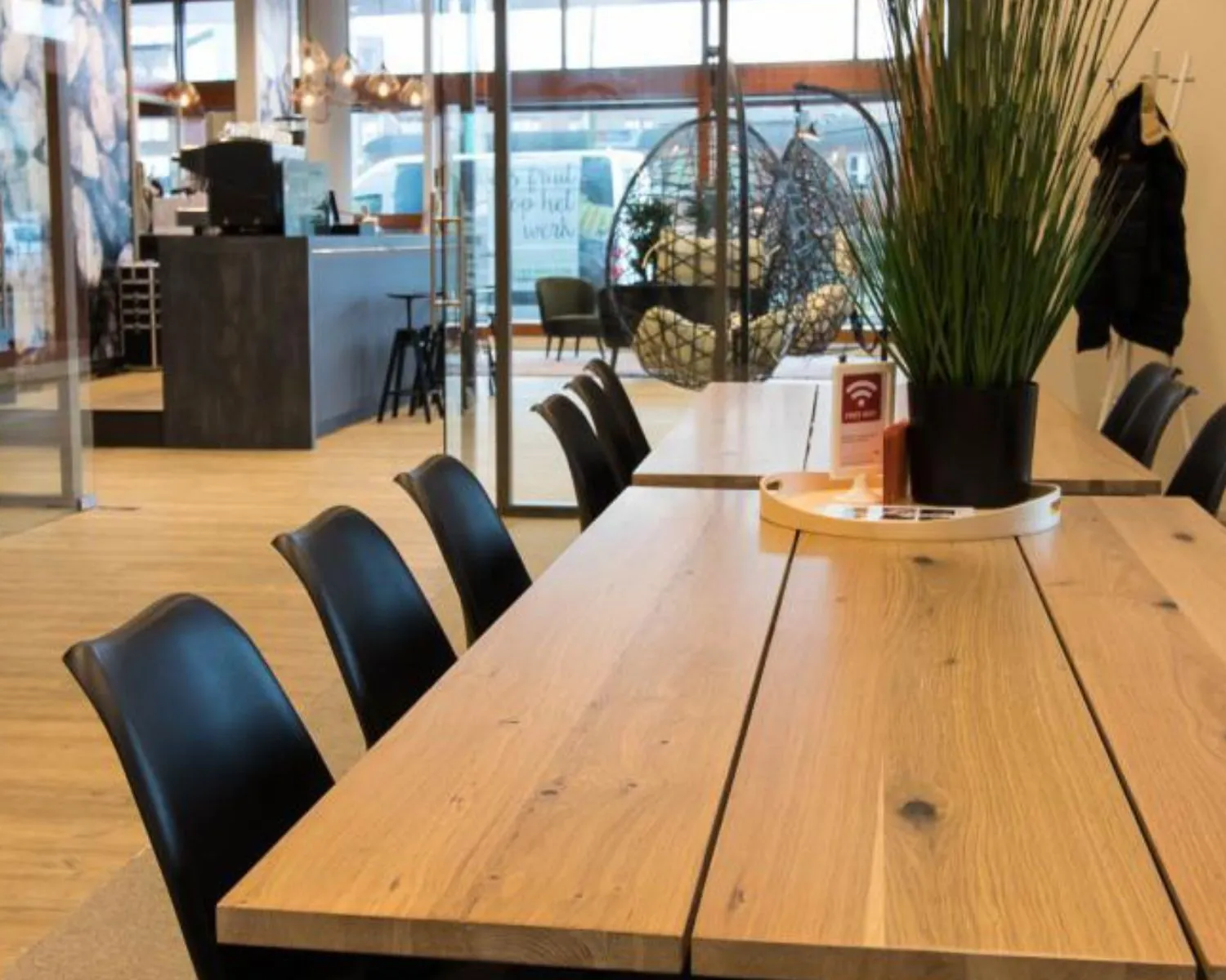 Moderne kantoorruimte aan het Smallepad 32 in Amersfoort met een lange houten vergadertafel, zwarte stoelen en een open loungegedeelte op de achtergrond.