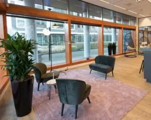 Moderne kantoorruimte aan het Smallepad 32 in Amersfoort met grote ramen, zithoek en houten vloer.