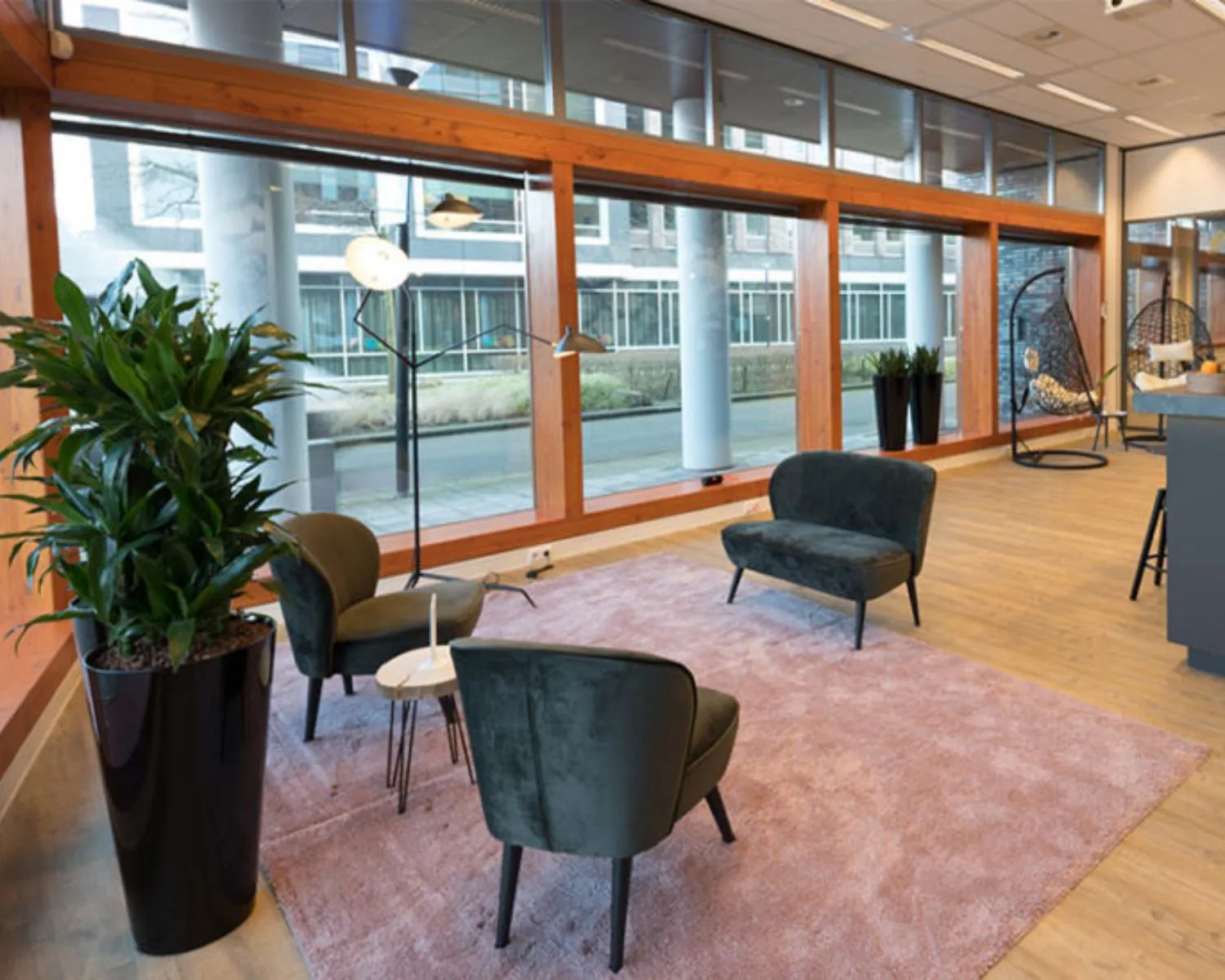 Moderne kantoorruimte aan het Smallepad 32 in Amersfoort met grote ramen, zithoek en houten vloer.