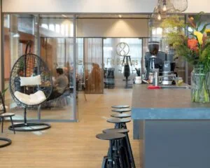 Moderne kantoorruimte aan het Smallepad 32 in Amersfoort met zithoek, bar en zicht op vergaderruimte en fitnessstudio Fit Boutiqs.