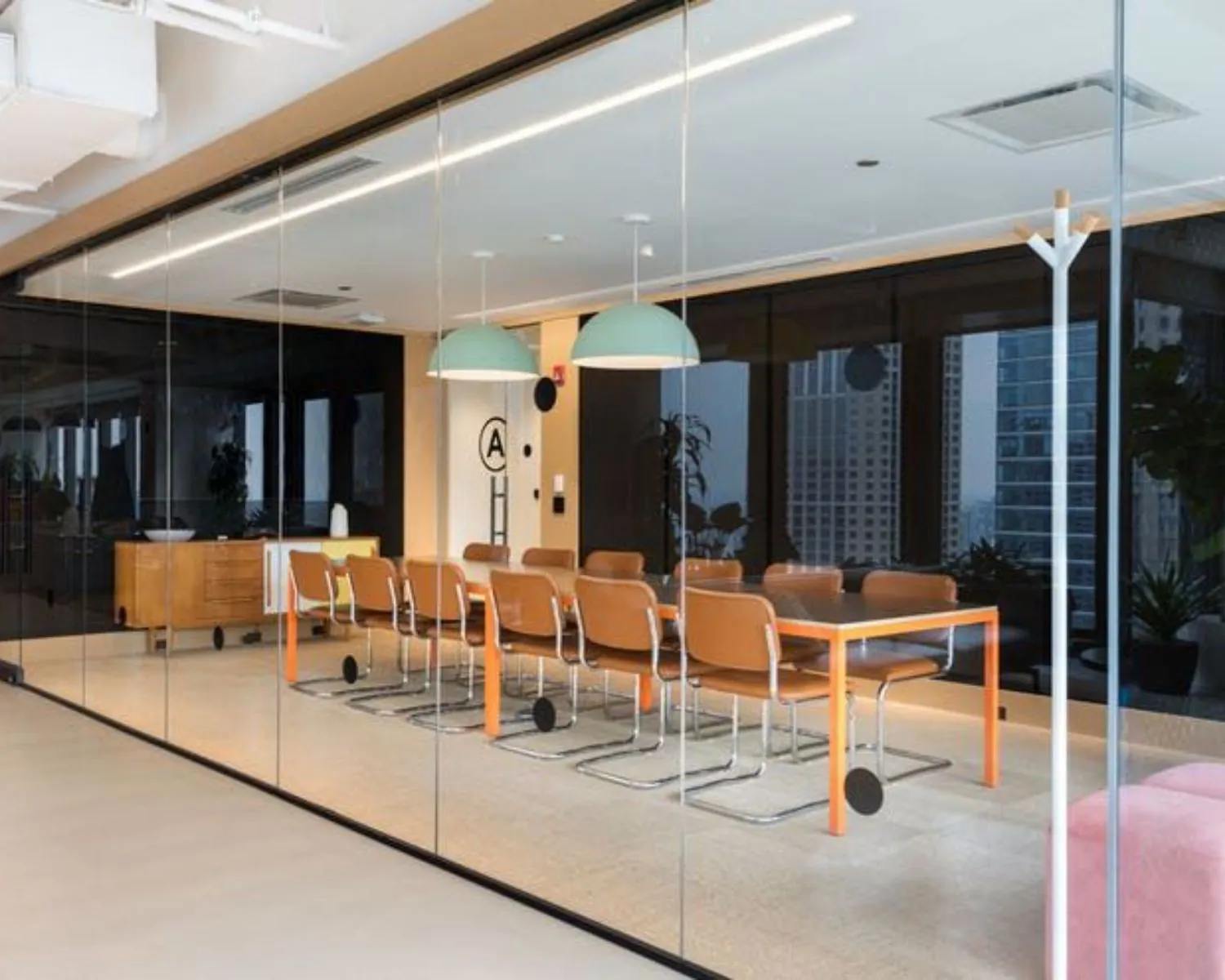 Moderne vergaderruimte met glazen wanden, oranje tafel en leren stoelen in een kantoor aan de Stadhouderskade in Amsterdam.