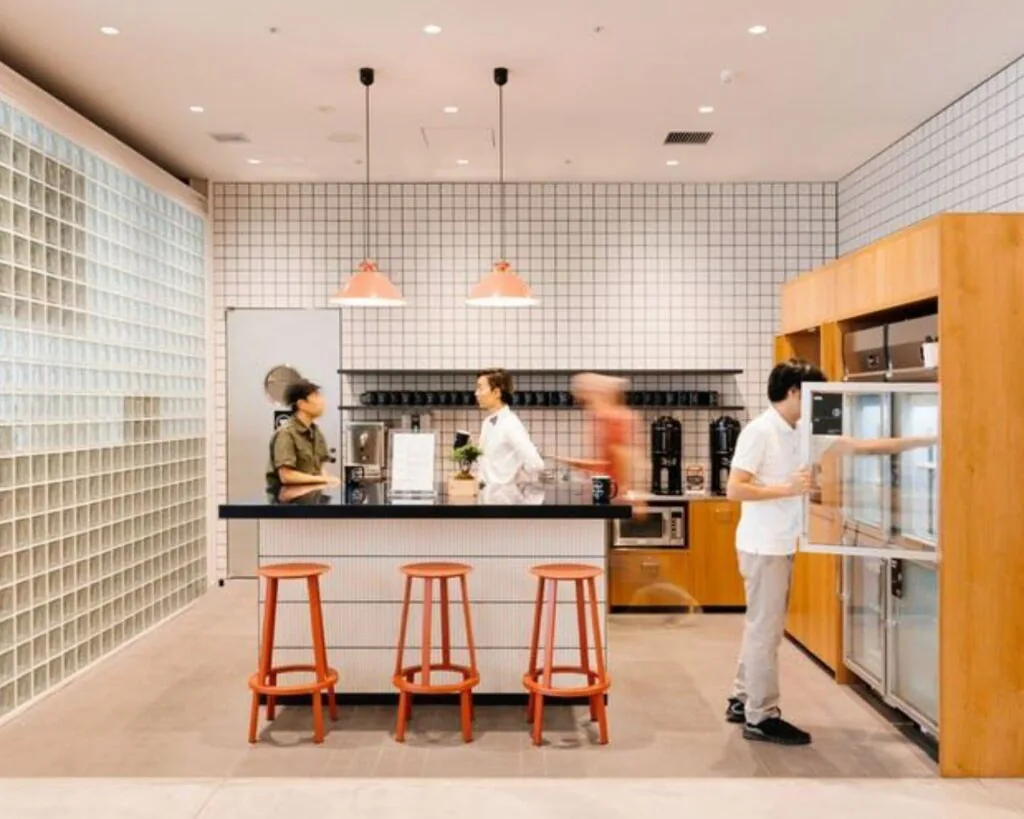 Moderne kantoorkeuken in een bedrijfsruimte aan de Stadhouderskade 5 in Amsterdam met mensen rondom een bar en open kasten.