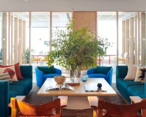 Moderne kantoorruimte aan de Stadhouderskade in Amsterdam met kleurrijke zitplekken, een grote plant en een vergaderruimte op de achtergrond.