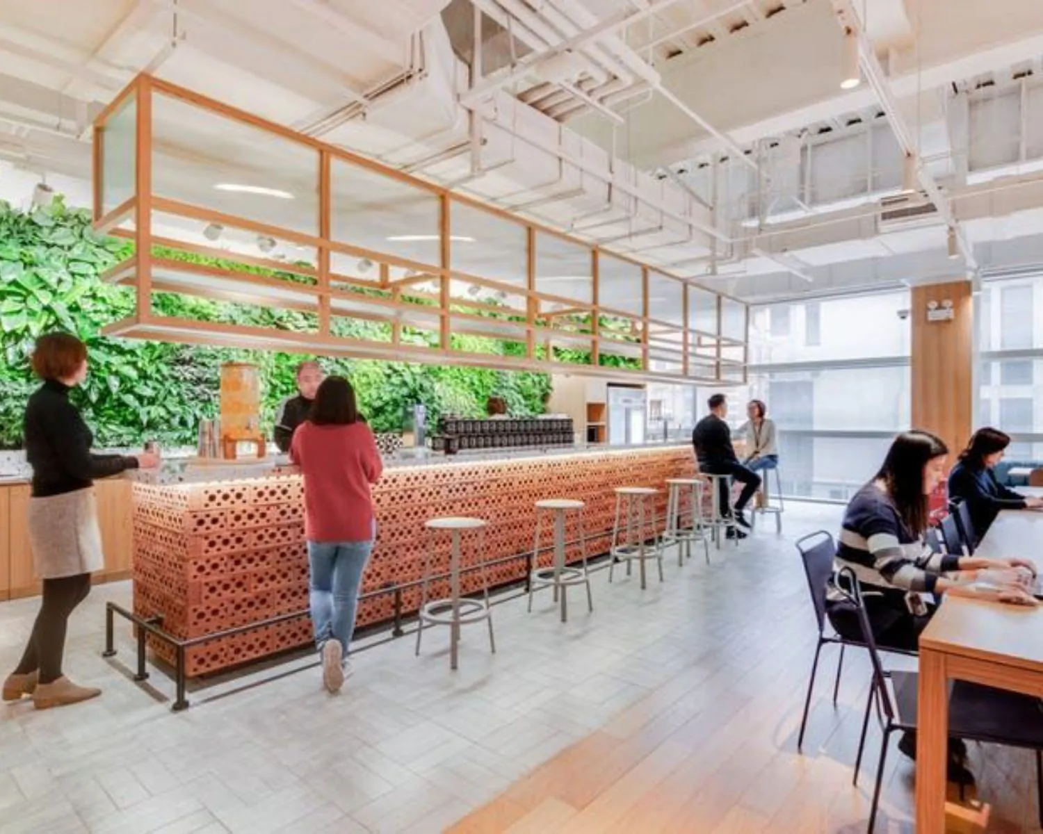 Moderne kantoorruimte aan de Stadhouderskade in Amsterdam met een open bar, zitplekken en een groene plantenmuur.