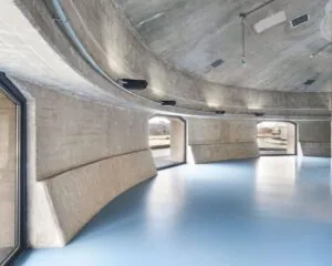 Moderne, industriële kantoorruimte in SugarCity Halfweg met betonnen muren, ronde vormen en grote ramen.