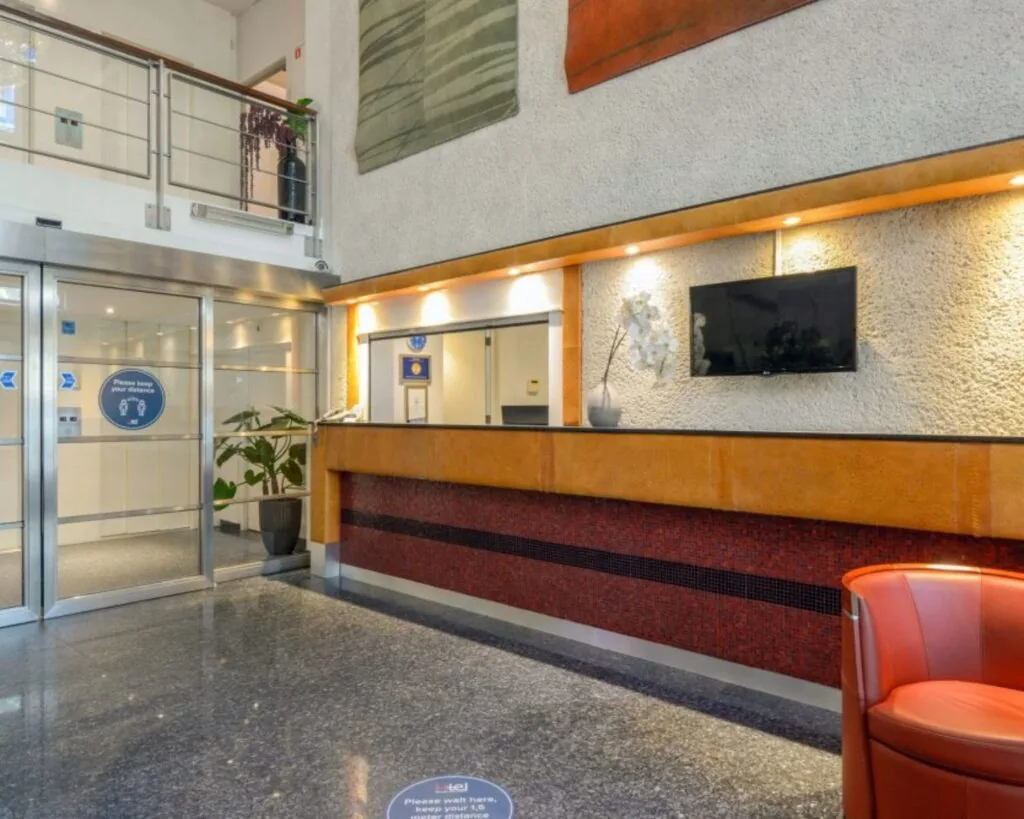 Moderne entreehal van een kantoorpand in Teijlingen met balie, zitgelegenheid en glazen schuifdeuren.