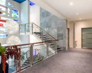 Moderne kantoorruimte met glazen trapleuning, kleurrijke wanddecoratie en opvallende hanglampen.