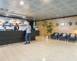 Moderne ontvangsthal van een kantoorpand aan de Tupolevlaan 41 in Schiphol met balie, zitgelegenheid en wereldklokken aan de wand.