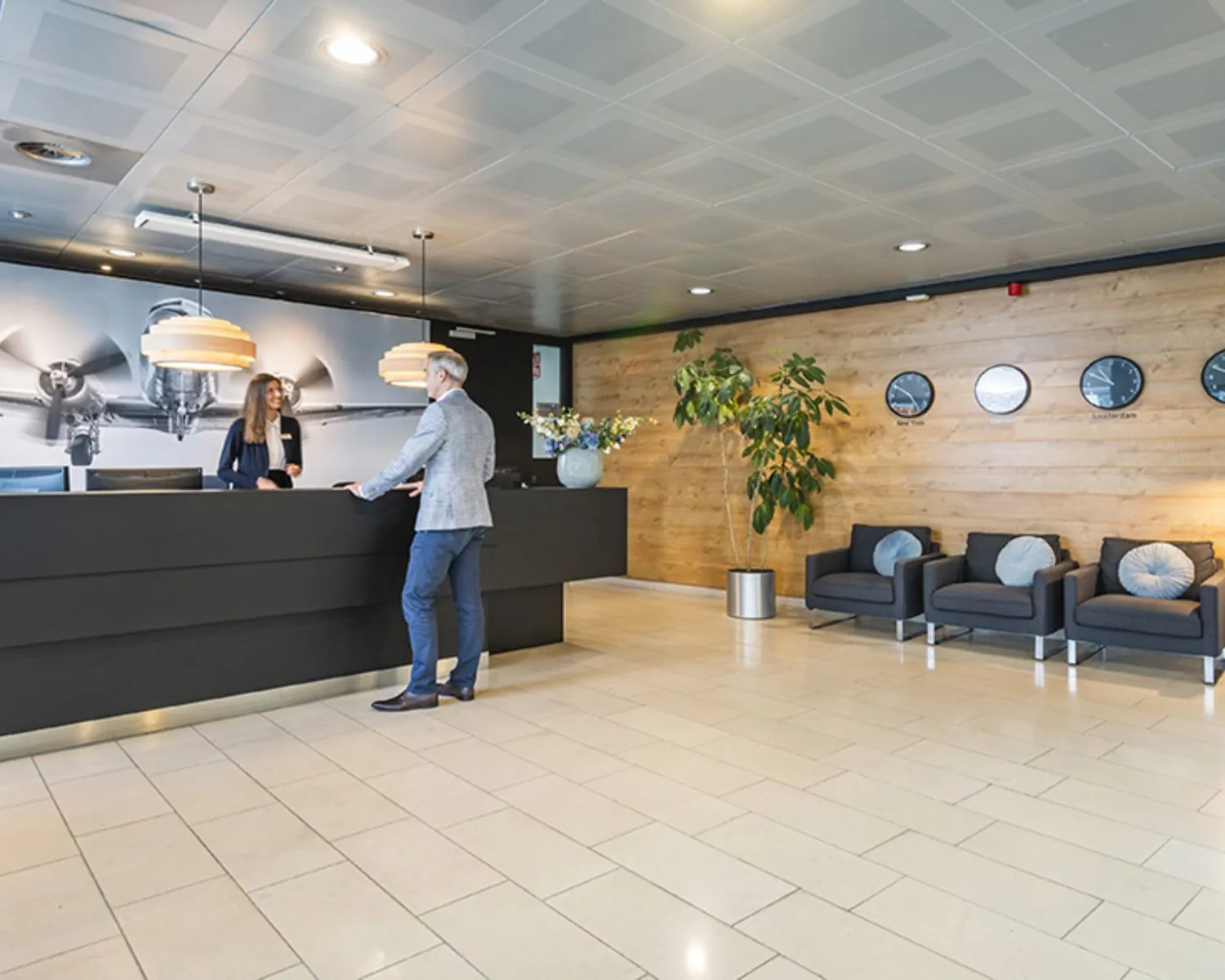 Moderne ontvangsthal van een kantoorpand aan de Tupolevlaan 41 in Schiphol met balie, zitgelegenheid en wereldklokken aan de wand.