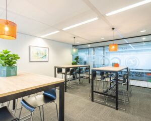Moderne, lichte kantoorruimte aan de Tupolevlaan 41 in Schiphol met hoge tafels, barkrukken en kleurrijke hanglampen.