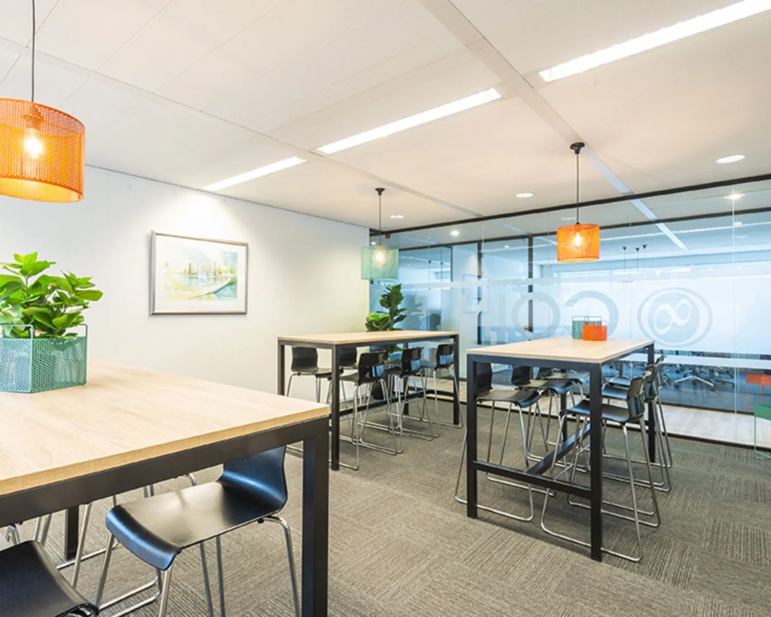 Moderne kantoorruimte met hoge tafels, barkrukken, hanglampen en glazen wanden aan de Tupolevlaan 41 in Schiphol.