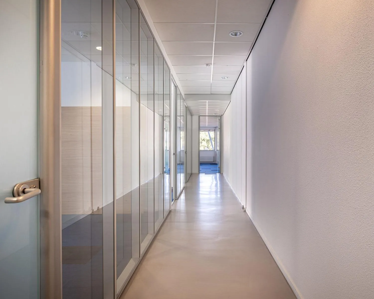Strakke, moderne gang met glazen kantoorwanden in een kantoorpand aan de Ukkelstraat 2 in Eindhoven.