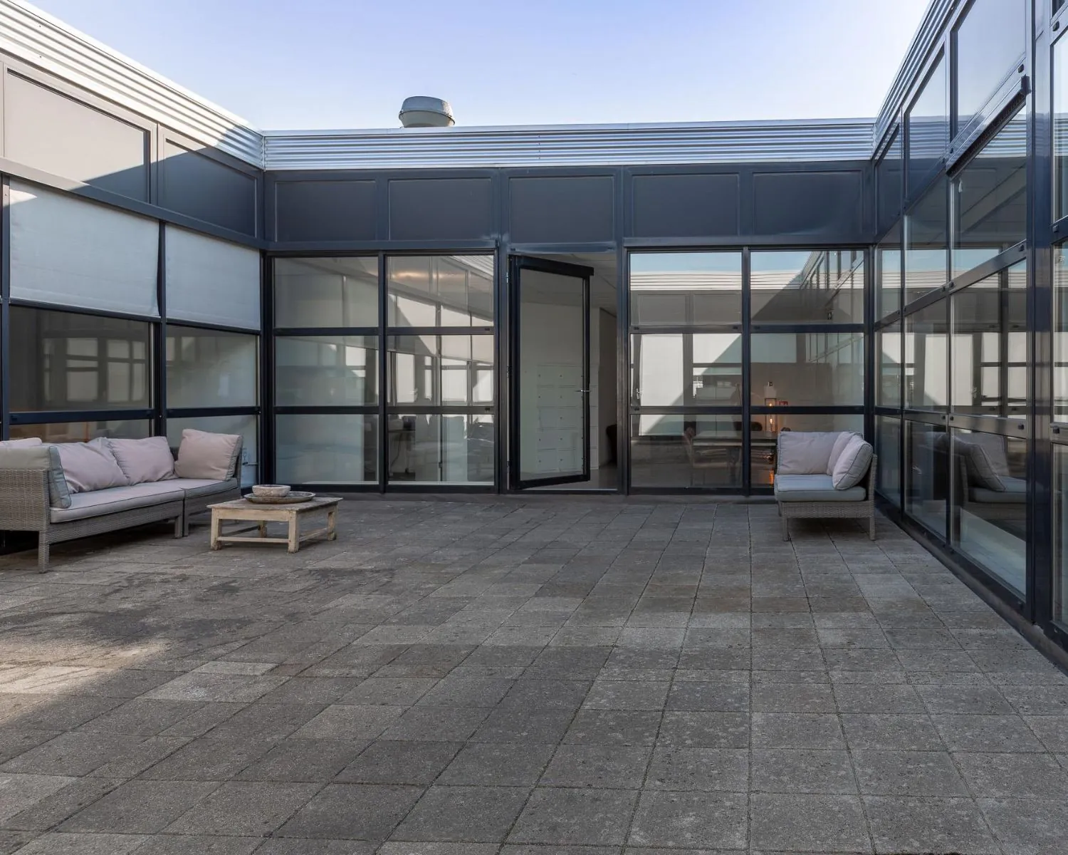 Ruim dakterras met zitbanken en glazen gevels bij kantoorruimte aan de Ukkelstraat 2 in Eindhoven.