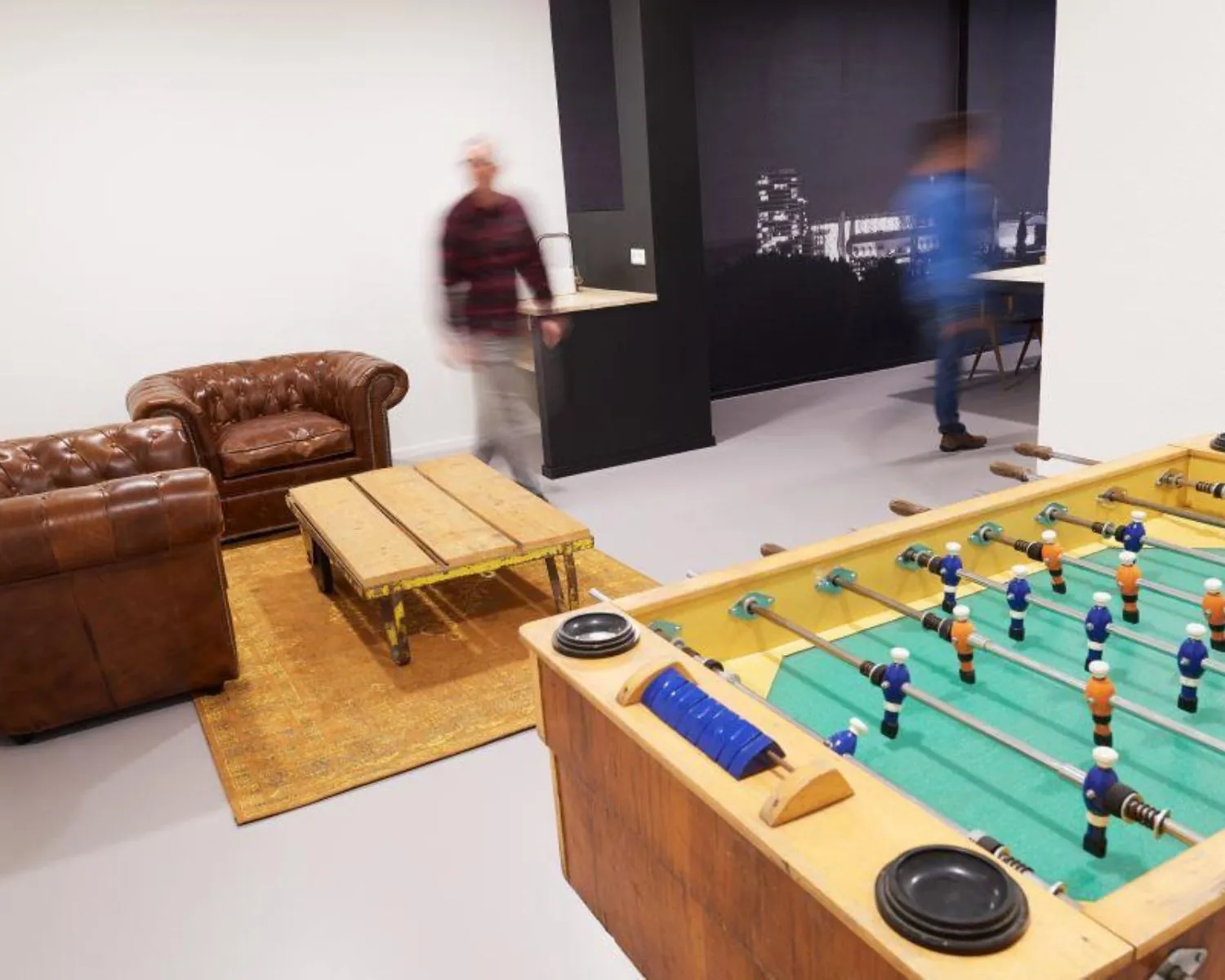 Gemeubileerde kantoorruimte aan de Ukkelstraat 2 in Eindhoven met leren zithoek, tafelvoetbaltafel en werkruimte op de achtergrond.