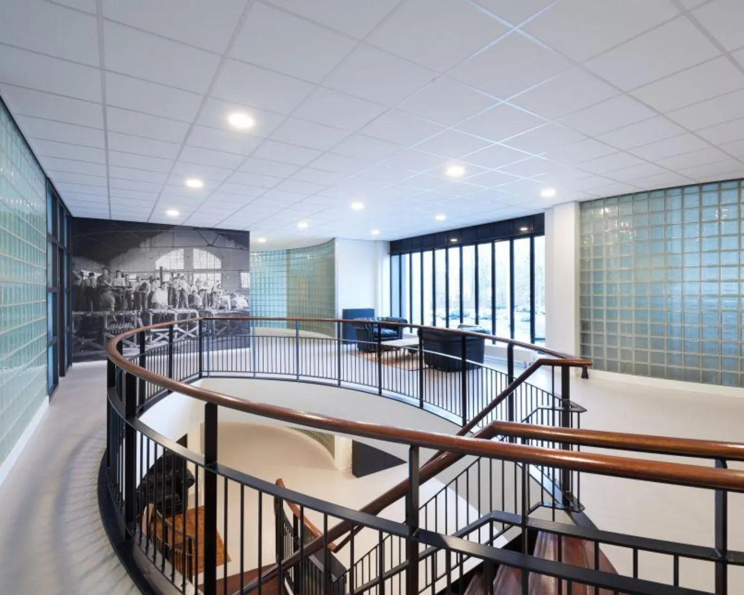 Moderne kantoorruimte met glazen bouwstenen, grote raampartijen en een ronde houten trap aan de Ukkelstraat 2 in Eindhoven.